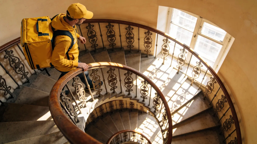 Курьер передает пакет с едой клиенту бесконтактным способом у двери Курьер передает пакет с едой клиенту бесконтактным способом у двери