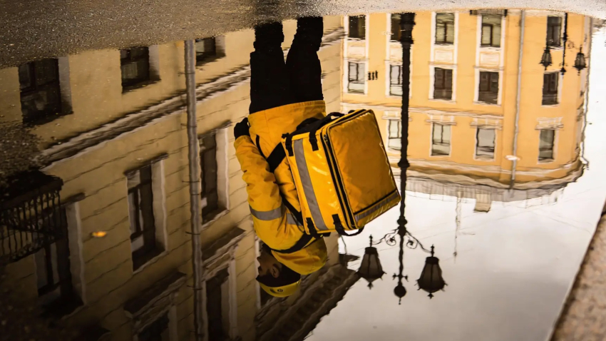 Курьер в фирменной куртке делает отчетное фото термосумки для приложения Курьер в фирменной куртке делает отчетное фото термосумки для приложения